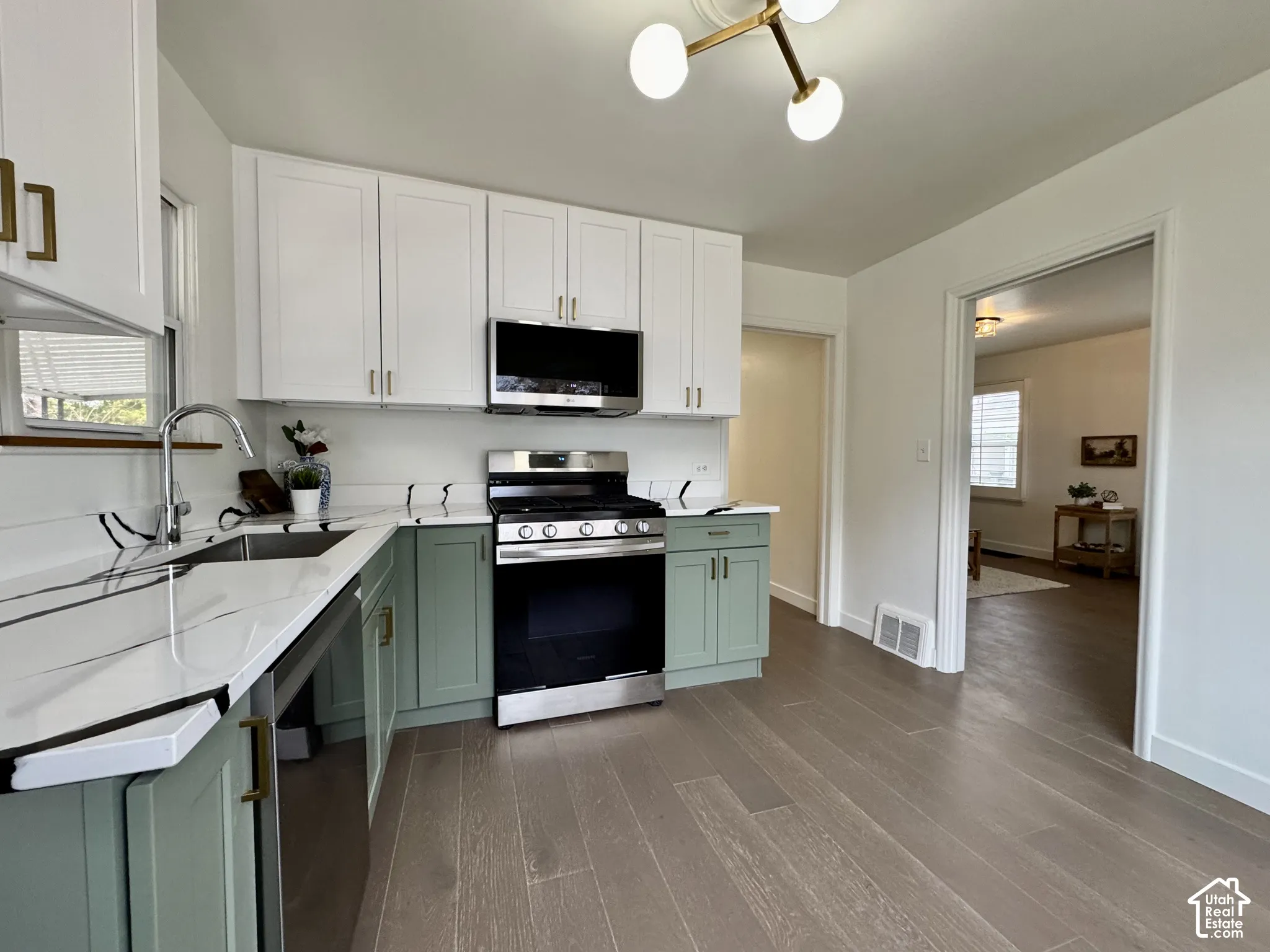Newly remodeled kitchen with new soft close cabinetry, real wood floors and stunning quartz countertops.Looking into living room and hallway