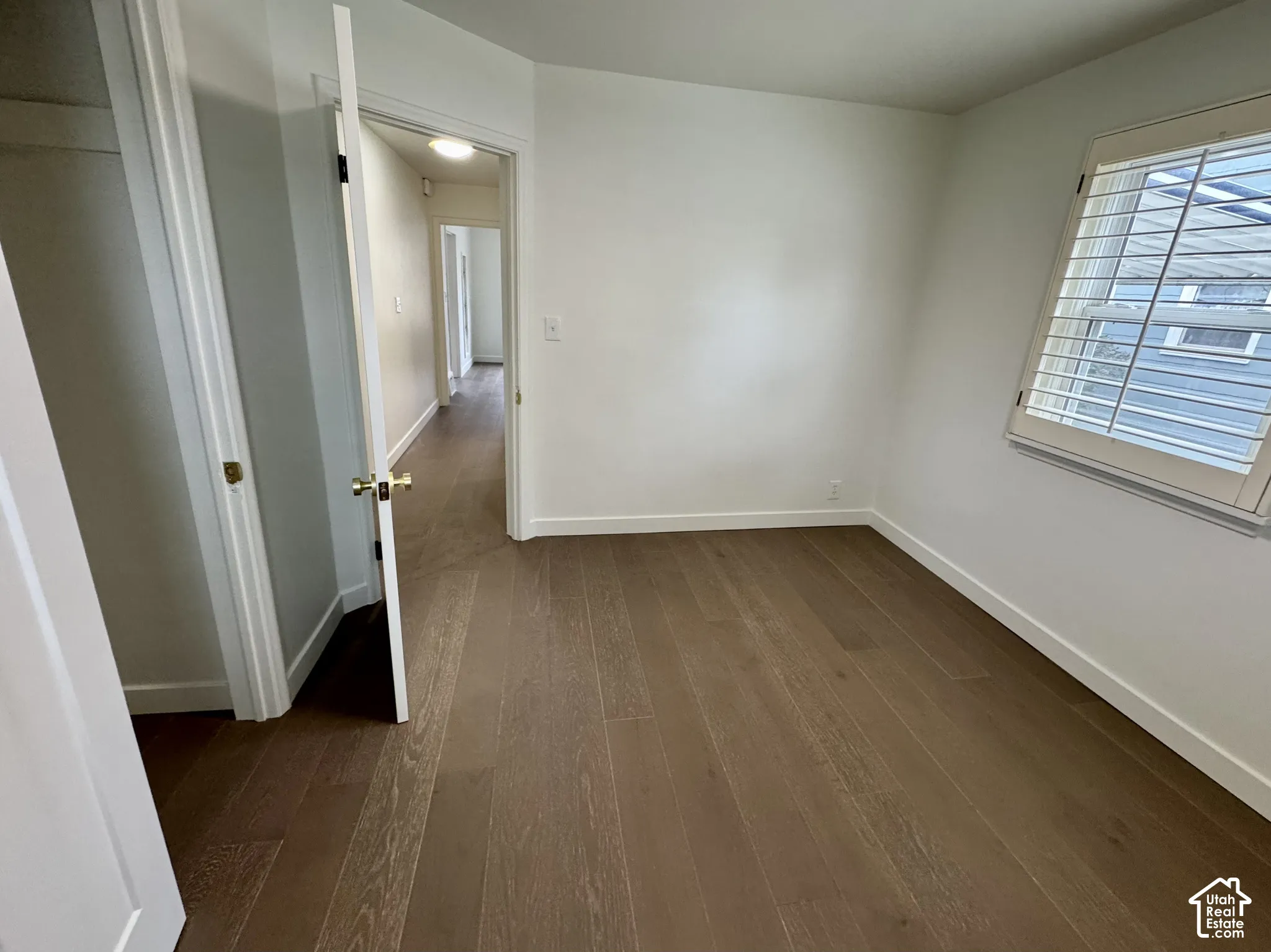 Main level bedroom with real wood flooring, white paneled doors, and window plantation shutters