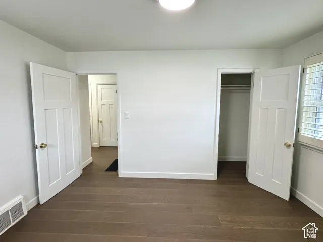 Primary bedroom with real wood flooring, white paneled doors, and window plantation shutters