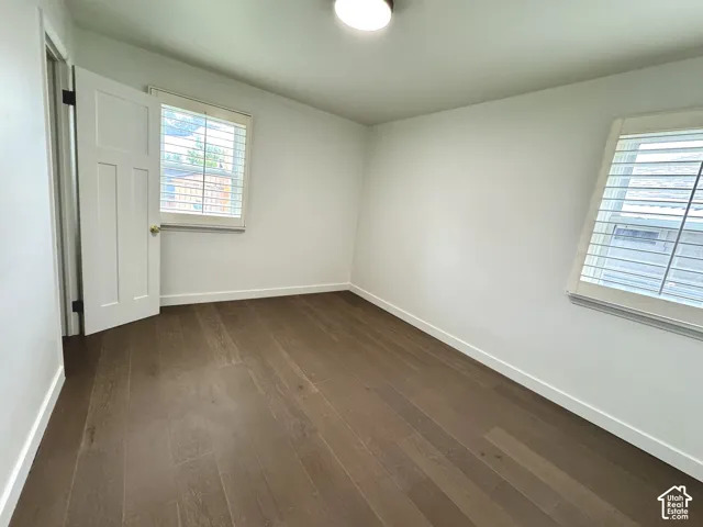 Primary bedroom with real wood flooring, white paneled doors, and window plantation shutters