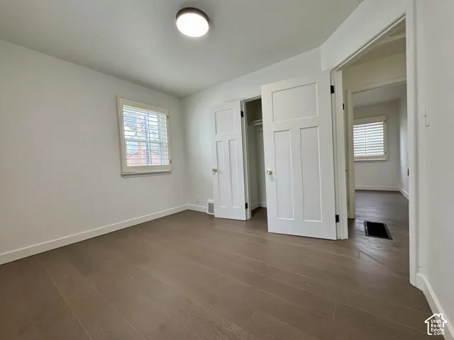 Main level bedroom with real wood flooring, white paneled doors, and window plantation shutters