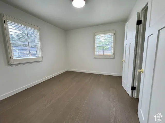 Main level bedroom with real wood flooring, white paneled doors, and window plantation shutters