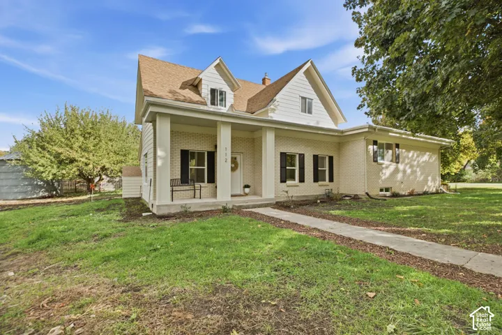 Two-story residence featuring a brick and horizontal siding exterior, a covered front porch with square columns, and a concrete walkway