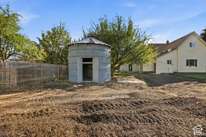 Exterior area featuring a metal grain silo, wood-lap siding residence, and perimeter wood fencing