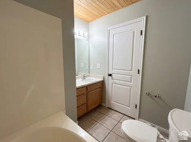Bathroom featuring a wood-plank ceiling, tile flooring, built-in wooden vanity with a stone-surfaced countertop, and a white paneled door