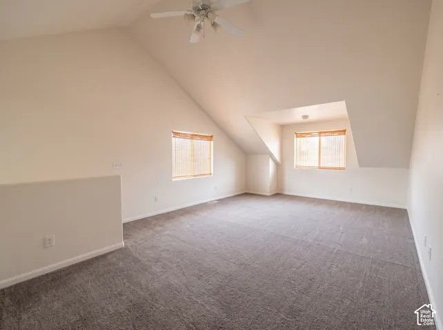 Vaulted ceilings, neutral carpeting, and a central ceiling fan