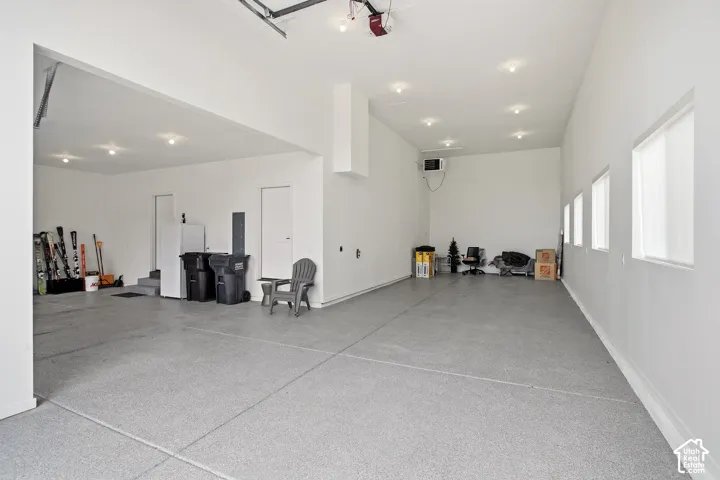 Spacious garage with light gray speckled flooring, multiple recessed light fixtures, and a series of high-set windows