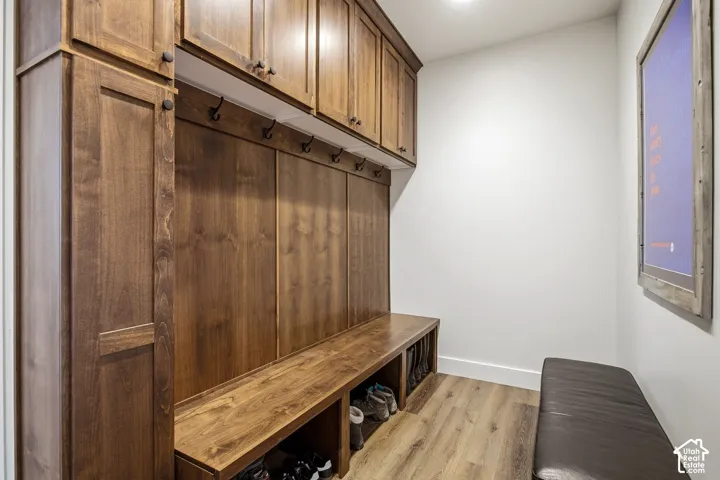 Custom built-in wood cabinetry with storage hooks, integrated bench seating, and wood-finish flooring