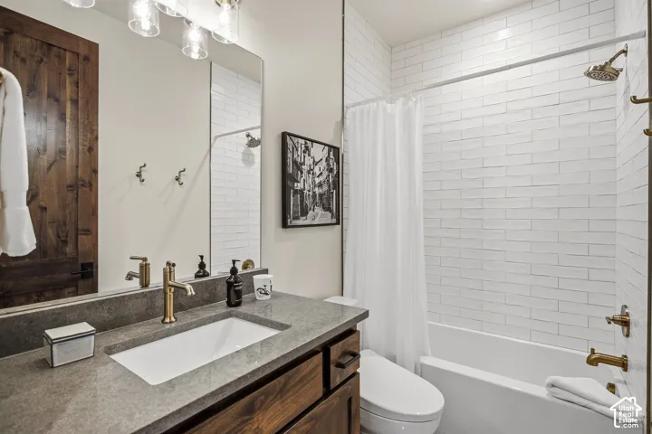 Bathroom featuring an integrated vanity sink, gray countertop, wood-finish cabinetry, and a subway tiled shower with a tub