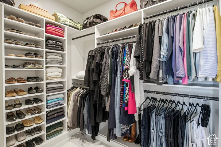 Built-in closet system featuring white shelving, multiple hanging rods, and integrated shoe racks