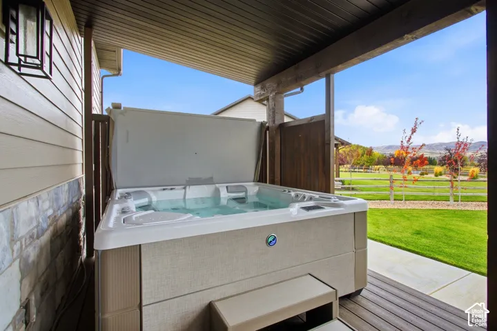 Covered deck with a hot tub and stone accent wall