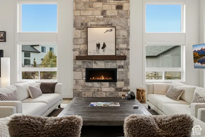 Stone-clad fireplace with a wood mantel and linear gas insert, flanked by tall windows