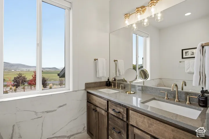 Double vanity with integrated rectangular sinks, dual brass-finish faucets, and a full-width mirror