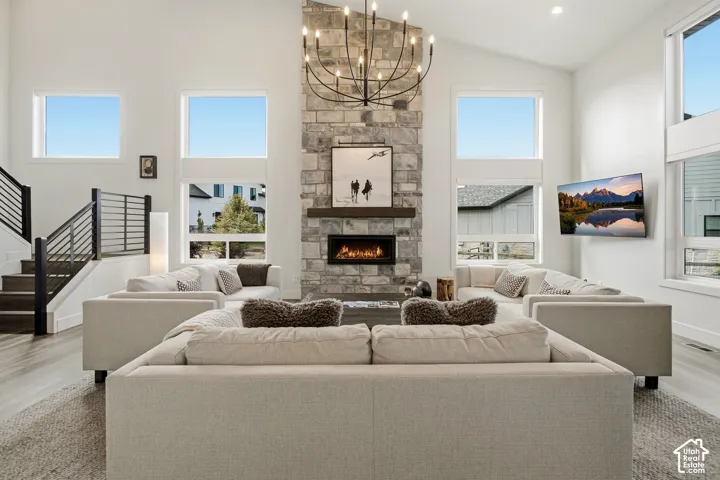 Two-story stone fireplace with an integrated linear firebox and wood mantel, complemented by a large chandelier