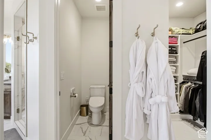Built-in closet shelving, recessed lighting, and a white toilet