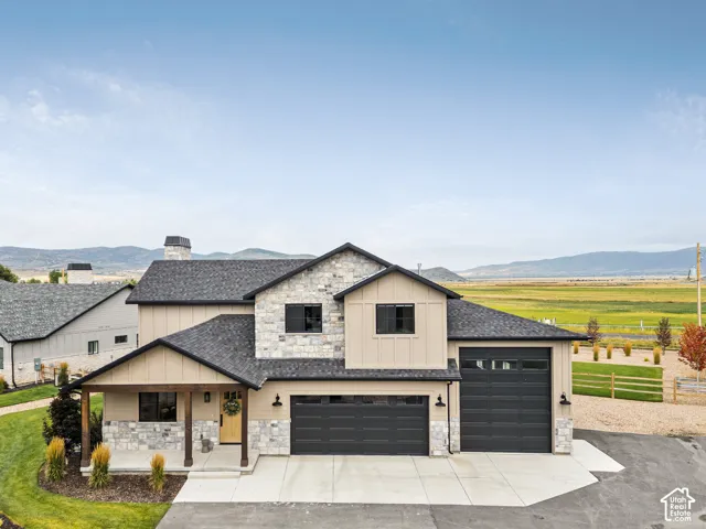 Modern two-story residence showcasing a mixed-material exterior combining stone and cream-colored siding, topped with a charcoal asphalt roof
