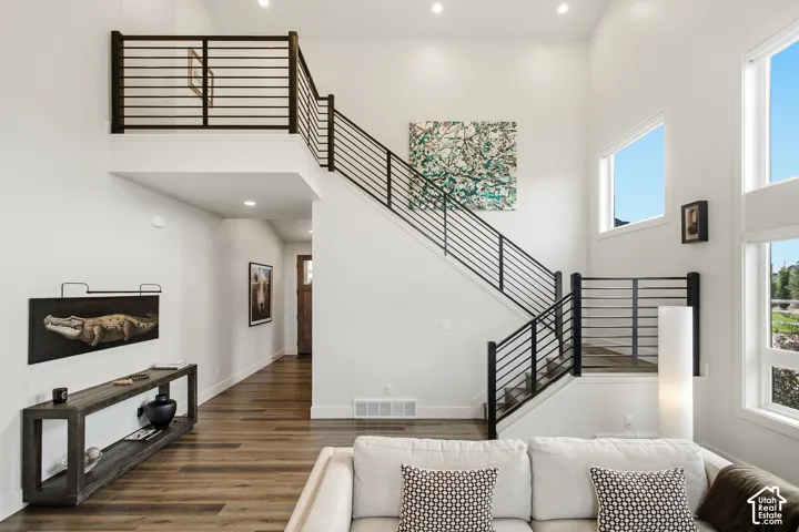 Two-story living space featuring high ceilings, wood-finish flooring, and a modern staircase with horizontal metal railings
