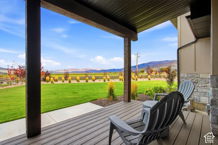 Covered deck with wood-finish flooring, sturdy support beams, and a stone facade