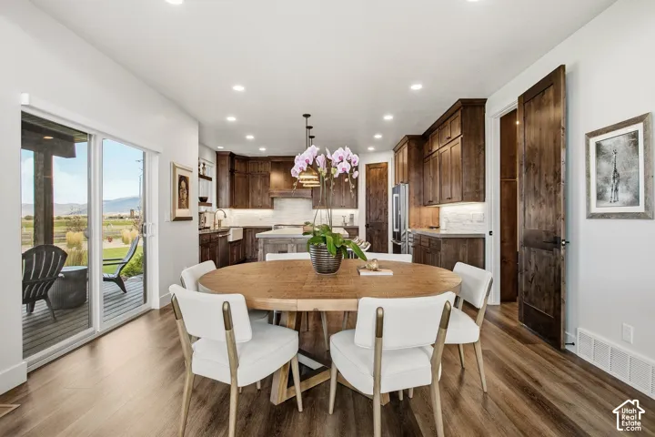 Open-concept dining area with wood-finish flooring, recessed lighting, and sliding glass door access to an exterior deck