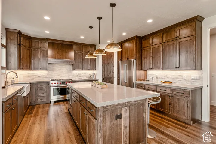 Gourmet kitchen featuring wood-finish cabinetry, stainless steel appliances, a center island with countertop seating, and recessed lighting