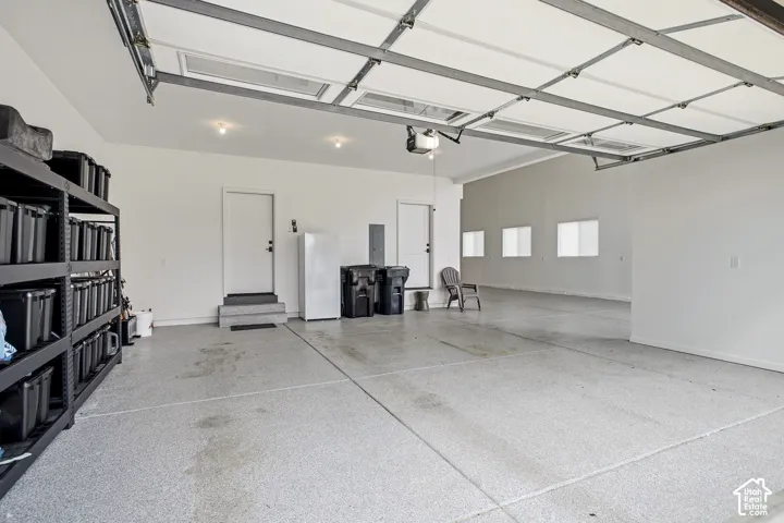Spacious garage featuring a finished floor, multiple windows, recessed lighting, and a large overhead door