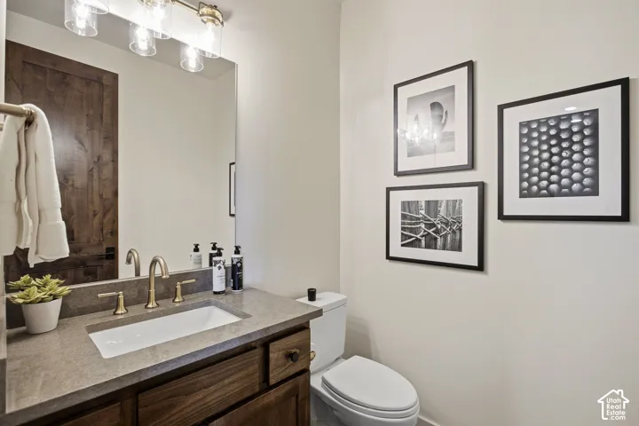 Wood-finish vanity with a rectangular undermount sink, brass-finish faucet, and coordinating vanity light fixture