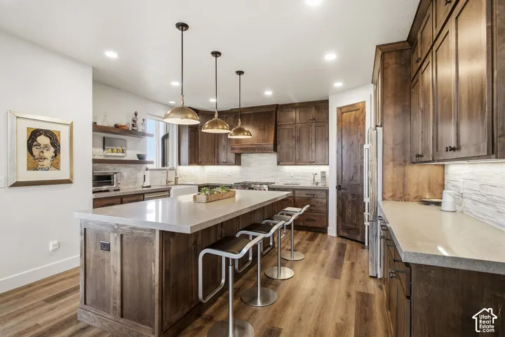 Kitchen featuring wood-finish flooring, wood cabinetry, a center island with a light-toned countertop, and recessed lighting