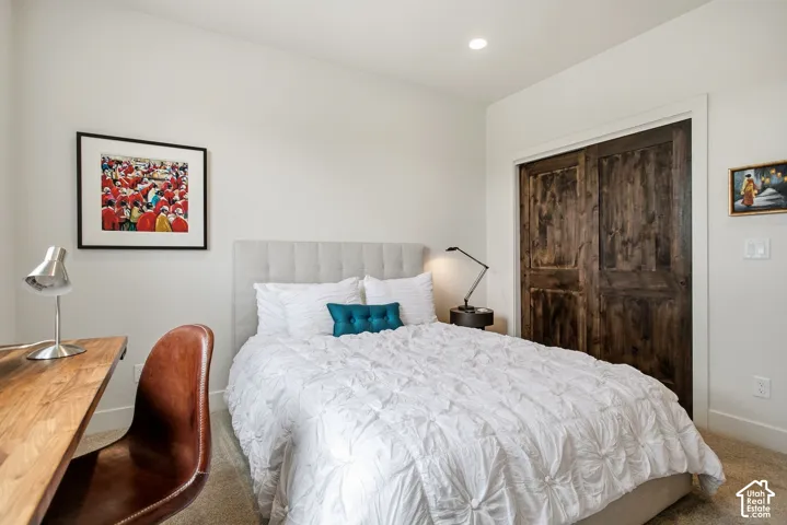 Recessed ceiling lighting, wood-finish sliding closet doors, upholstered headboard, and neutral wall paint