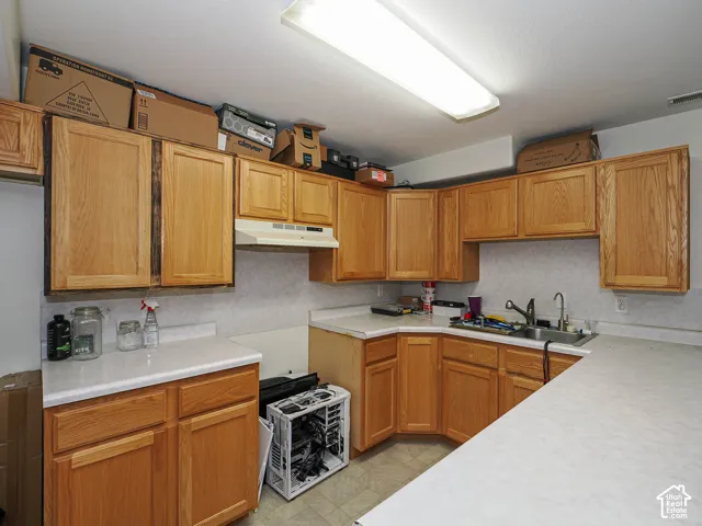 Spacious kitchen featuring warm wood cabinetry throughout, laminate countertops, gas range cooktop, undermount sink with faucet, and abundant storage