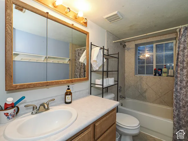 Bathroom featuring a wood-framed medicine cabinet, laminate countertop with an integrated oval basin, light wood cabinetry, and a bathtub with tiled surround