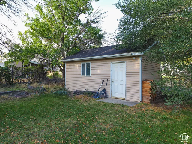 Detached storage structure featuring vinyl siding, a gable roof, and a single-entry door with a concrete landing