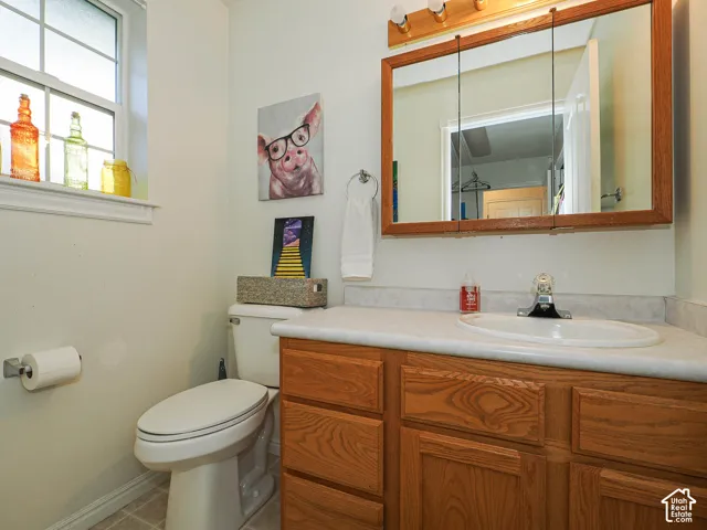 Wood-finish cabinetry with a countertop, integrated vanity sink, mirrored medicine cabinet, and window with muntin detailing