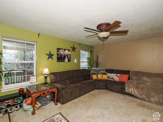 Living space featuring dual-pane windows, a ceiling fan with integrated lighting, and neutral wall-to-wall carpeting