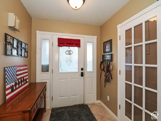 Entryway featuring a white exterior door with decorative glass inserts and sidelights, tile flooring, and a French door with multiple glass panes