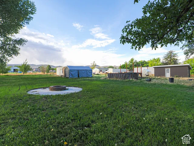 Expansive backyard featuring a circular stone fire pit and multiple outbuildings