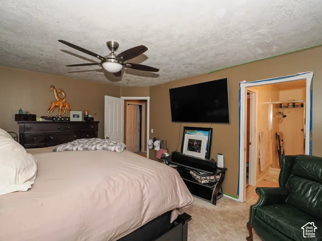 Room featuring a textured ceiling, brushed nickel ceiling fan with dark blades, and two interior doorways