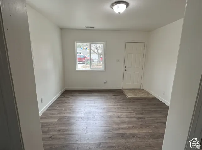 Interior space featuring wood-finish flooring, neutral wall tones, a sliding window, a flush-mount ceiling light fixture, and a tiled entry area