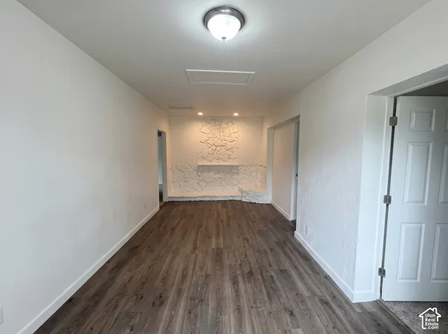 Interior featuring wood-finish flooring, white textured walls, stone-accented hearth, and recessed lighting