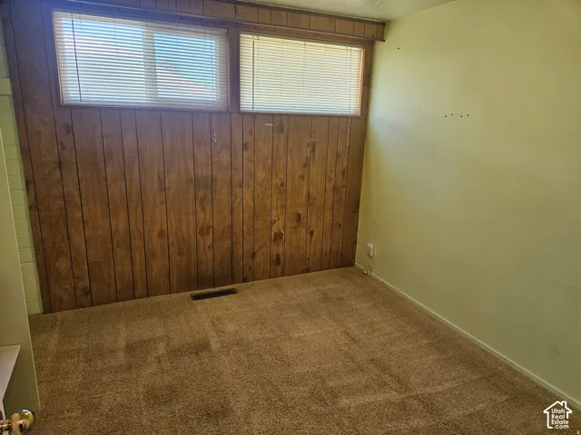 Textured wall paneling, dual horizontal windows with integrated blinds, and neutral carpeting