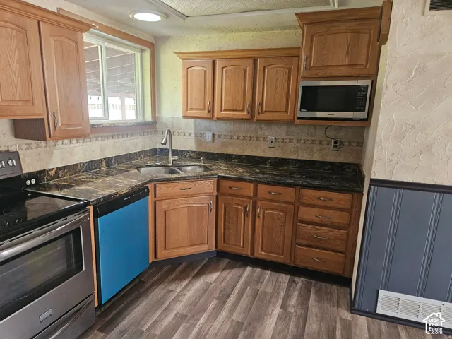 Kitchen featuring wood cabinetry, stone-finish countertops, tile backsplash, built-in microwave, and wood-finish flooring