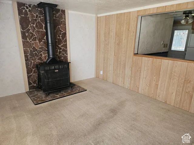 Freestanding wood-burning stove with a stone surround, stone hearth, light-tone wood paneling, and interior pass-through window