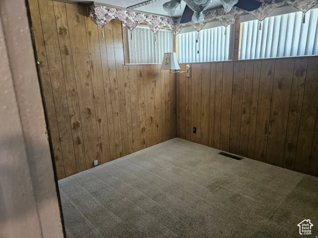 Wood-paneled interior walls, wall-to-wall carpeting, high-placed horizontal windows with vertical blinds, and a hard-wired brass wall sconce
