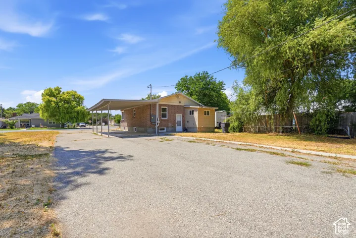 Single-story exterior featuring a brick and siding facade, covered carport, and asphalt driveway