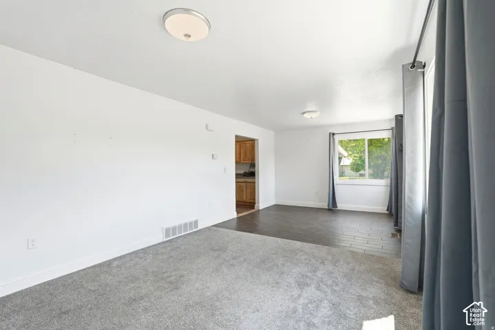 Living area featuring neutral carpeting, dark wood-finish flooring, sliding window, and dual flush-mount ceiling light fixtures