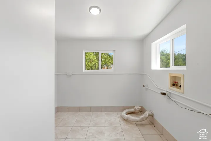 Utility room featuring tile flooring, dual sliding windows, neutral wall finishes, flush-mount lighting, and recessed laundry hookups