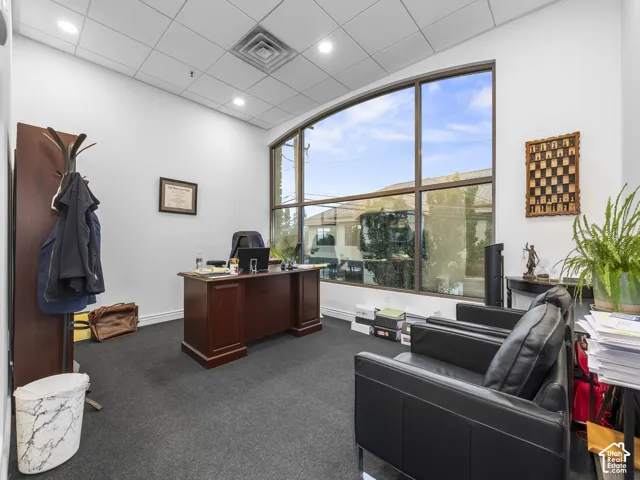 Office space featuring floor-to-ceiling windows, dark carpeting, and recessed ceiling lighting