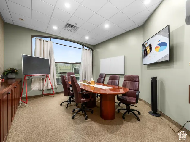 Conference room featuring integrated recessed lighting, a drop ceiling, carpeted flooring, and a large arched window