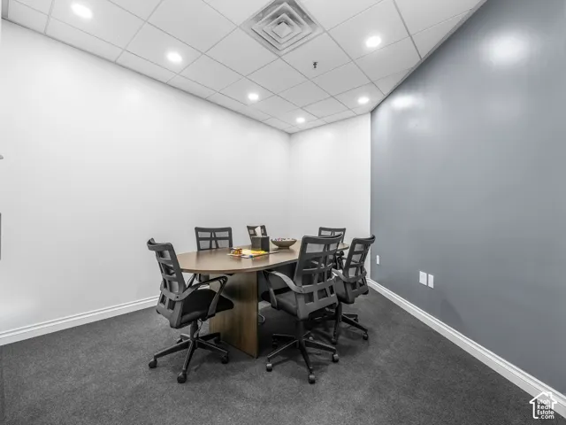 Drop ceiling with recessed LED lighting, charcoal carpeting, and a prominent grey accent wall