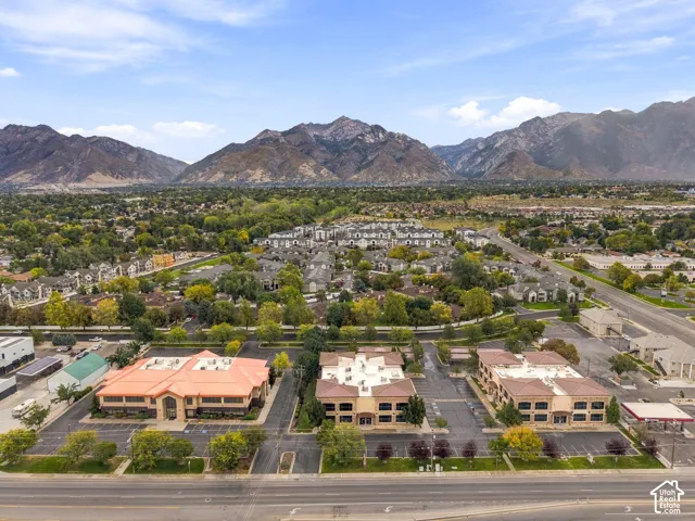 Aerial perspective featuring commercial structures with paved parking lots and prominent mountain backdrop