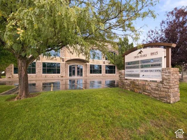 Commercial office building featuring a stone and stucco facade, multi-pane window systems, arched entryway, and a stone-clad monument sign
